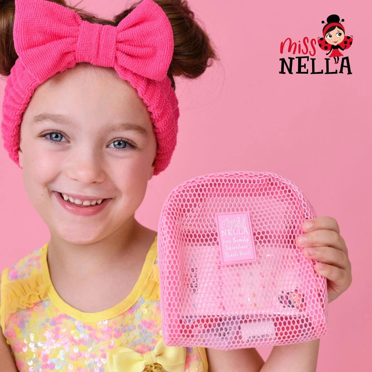 Mädchen mit pinkem Stirnband hält den pinken Mesh-Kulturbeutel von Miss Nella mit Schminke darin